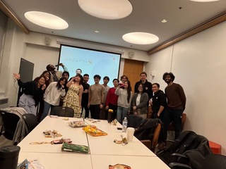 seventeen people posing for a picture in front of a projection screen